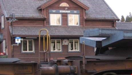 Två tågvagnar framför ett brunt hus.
